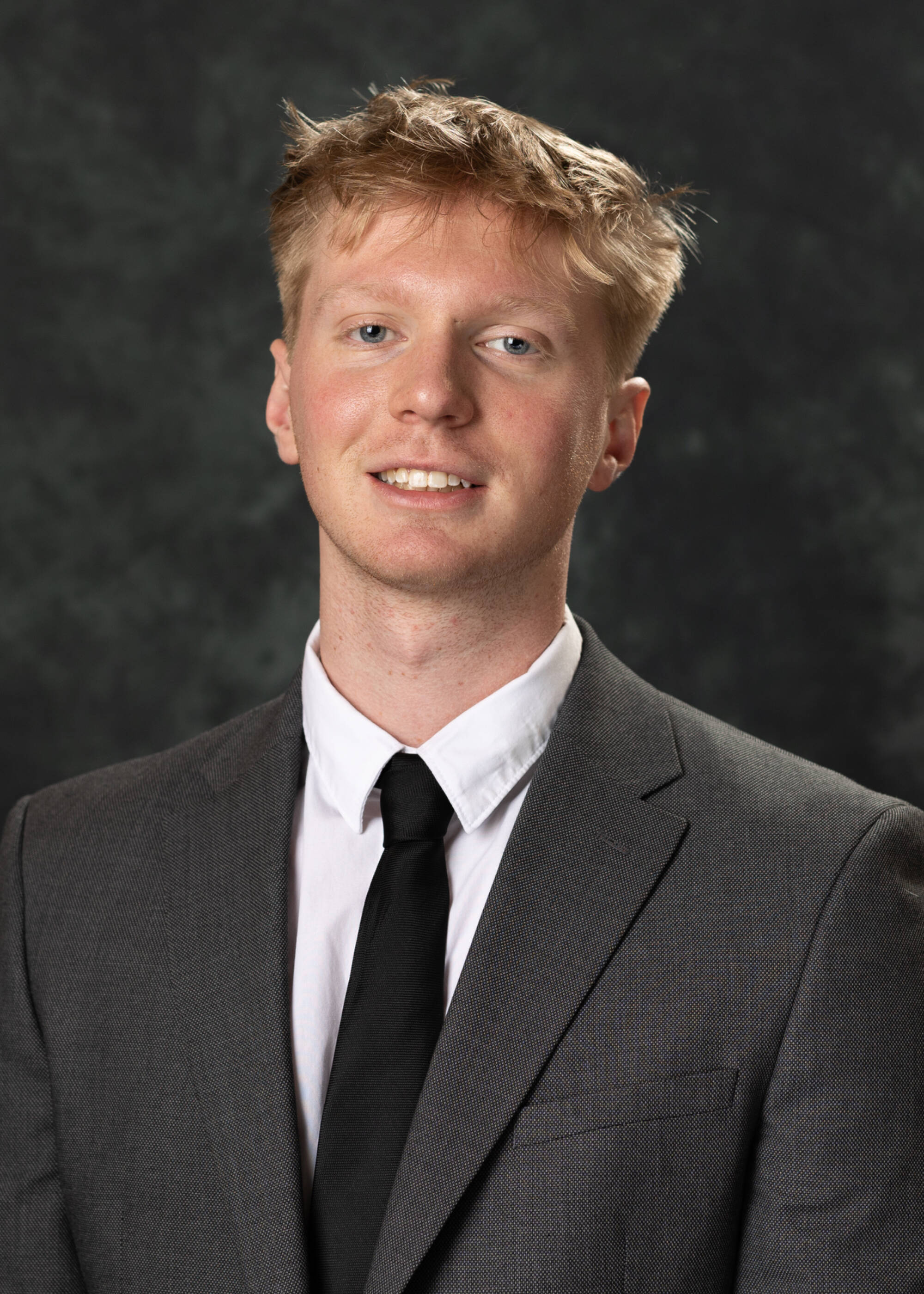 Lukas Hartley smiling in a gray suit